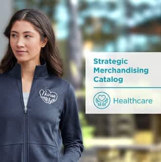 A woman in a navy jacket with a heart logo that reads 'Nurses bring love, standing next to a sign that says Strategic Merchandising Catalog - Healthcare