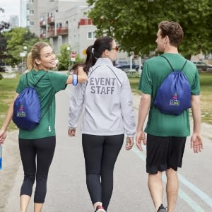 2 ladys and 1 guy walking on the street wearing Drawstring bag image