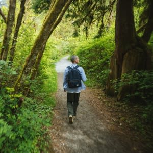 A man walking in a park wearing backbag image